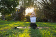 © leungchopan - Woman doing yoga sitting on green park grass