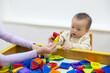 © leungchopan - Baby playing with colorful magnet tiles in indoor playhouse