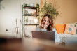 © Dusan - Woman working remotely smiling using laptop at home