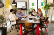 © Nikola Spasenoski - Meeting of creative professionals discussing project ideas in a modern office space with plants and technology around them