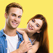 © vgstudio - Happy smiling cute couple. Portrait of standing close embracing boyfriend, girlfriend in love studio concept, isolated yellow background. Young man and woman posing together. Square image