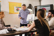 © Nikola Spasenoski - Businessman presents marketing strategy during a team meeting in a modern office space with engaging visuals and attentive colleagues