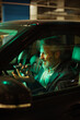 © Marko Geber - Mature man smiling, using voice assistant in car at night
