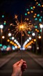 © NoorArt Studio - Hand holding a lit sparkler against a bokeh night background
