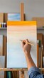 © NoorArt Studio - Artist hand painting sunset gradient on canvas easel