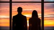 © NoorArt Studio - Silhouette of business couple looking at sunset through window