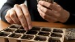 © StockShift - Close-up of an Asian adult's hands carefully planting tiny seeds into a biodegradable seedling tray indoors, embodying home-life mastery and a sustainable modern lifestyle with cinematic lighting.