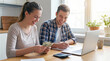 © MrLynx - Young couple managing finances together at home with laptop and calculator