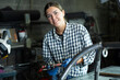 © JackF - Young girl, professional technician with clamp in hands, wearing checkered shirt and gloves, posing in industrial metal workshop, smiling confidently and friendly at camera..