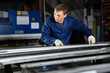 © JackF - Male worker at metallurgical plant measures an iron sheet using tape measure and marks the cutting line