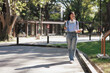 © Phimwilai - Female student walking on campus carrying books and smartphone