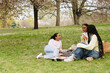 © Drobot Dean - A female student lies and talks to two female students sitting next to her on a blanket