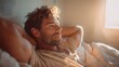 © Maryna - Man is laying in bed with his arms over his head. He has a smile on his face and he is relaxed