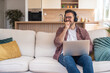© Srdjan - Smiling freelancer with headphones working on laptop in home office, enjoying remote work, online collaboration and flexible lifestyle