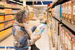 © Jordi Salas - Senior woman reading label of cereal box in supermarket
