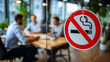 © Maksym - Close-up of a no smoking sign on glass door, red and white design clearly visible, background softly blurred showing people collaborating at a desk in a sunlit office