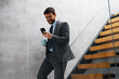 © Novak - Commuter on Stairs Checking Phone and Holding Coffee Cup