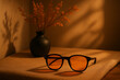 © 121icons - Stylish sunglasses with orange tinted lens placed on fabric with decorative vase shadows concept of fashion lifestyle style and personal accessories