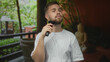 © Krakenimages.com - Man shaves beard with electric razor while holding the razor to his jaw in a hotel building; grooming confidence.