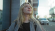 © Krakenimages.com - Woman standing on a bustling city street looking upwards with a thoughtful expression during daylight.