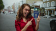 © Krakenimages.com - Woman holding korean passport outdoors showing thumb up while smiling on city street background.