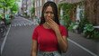 © Krakenimages.com - Woman in red crop top with hand to mouth for nausea on city street with brick houses and bicycles; disgust nausea.