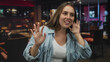 © Krakenimages.com - Young caucasian woman pressing hands to ears in restaurant, wincing at loud music and background chatter; discomfort.