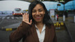 © Krakenimages.com - Smiling woman in brown blazer waves hand at airport curbside dropoff zone greeting passersby; friendly greeting.