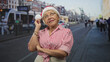© Krakenimages.com - Woman in santa hat with hand on chin thinking on a busy city street by a tram and cars, arms crossed and wearing a red striped shirt; pensive reflection.