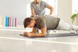 © Studio Romantic - Male nurse, caregiver or physiotherapist helping young man in doing sport plank exercise on yoga mat in rehabilitation clinic supporting him in rehab. Physiotherapy and recovery concept concept.