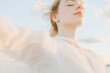 © World of AI - 2026 color trend. White woman in a flowing white suit dances gracefully against a soft sky backdrop, embodying freedom and joy in a serene outdoor setting with gentle breezes