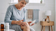 © D-point - Woman applying cream on her knee. Senior woman uses topical ointment for joint pain or arthritis relief. Elderly healthcare and self-care.