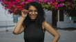 © Krakenimages.com - Woman smiling outdoors with curly hair and glasses, surrounded by vibrant flowers, showcasing natural beauty and confidence in a bright, colorful setting.