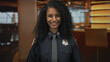 © Krakenimages.com - Officer smiling warmly in hotel lobby showcasing professional uniform setting vibrancy indoors woman police smiling confident young curly energy