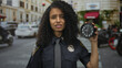 © Krakenimages.com - Policewoman holding clock with perplexed expression on urban street showcasing time management challenges faced by law enforcement in bustling city environment