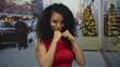 © Krakenimages.com - Woman in red dress playfully posing with boxing stance on festive street background with christmas trees, confidently smiling.