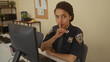 © Krakenimages.com - Hispanic woman police officer in dark blue uniform places finger to lips for silence in station building; quiet vigilance.