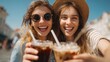 © Pavel - Cheerful young women enjoy iced coffee together in a sunny outdoor setting, celebrating friendship and joy on a warm afternoon