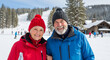 © Cliff - Portrait of a happy senior pensioner with her husband enjoying winter vacation on the background of a ski resort, concept of winter holidays and for the elderly. Hello winter. Pensioner's vacation
