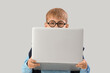 © Pixel-Shot - Little schoolboy with laptop studying computer sciences on light background