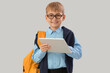 © Pixel-Shot - Little schoolboy with tablet computer studying computer sciences on light background