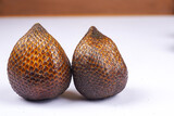 Two fresh salak fruits on a white surface in close-up view