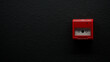 © slexp880 - Red manual fire alarm call point mounted on a modern textured black wall. Emergency safety button behind glass with negative space for text. Photo