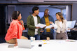 © Wavebreak Media - Diverse coworkers in business attire collaborating around table in office with laptops and papers