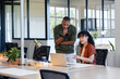 © Wavebreak Media - Colleagues collaborating at open-plan office desk, pointing at laptop screen with coffee mug