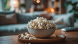 © Sadia - A bowl of popcorn sitting on a wooden tray in a living room with a couch and a remote control nearby