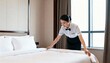 © Anim - hotel housekeeper making bed in clean and modern guest room