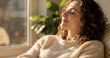 © Liana - Calm lifestyle moment of a woman relaxing with eyes closed in warm sunlight, wearing a cozy sweater in a peaceful indoor setting. Soft natural lighting, serene mood and premium editorial style perfect