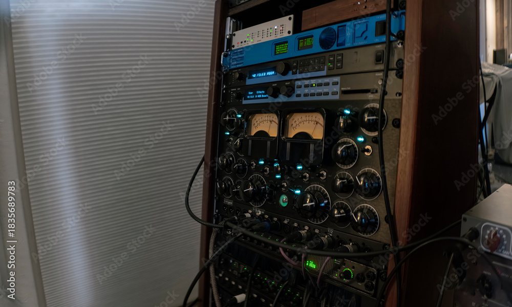 Rack-mounted vintage audio processing equipment with VU meters and ...