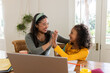 © Wavebreak Media - High-fiving mother and daughter while working at home dining table with laptop and orange juice